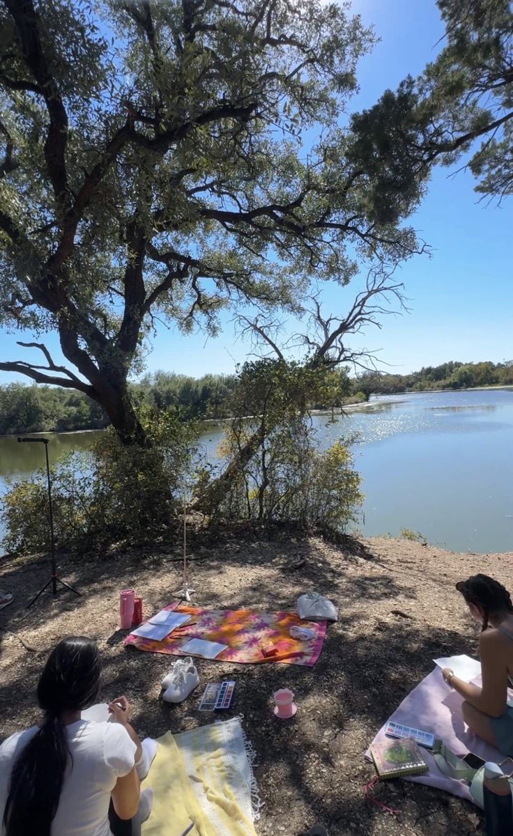 Watercolor journaling on blankets under a tree by the lake