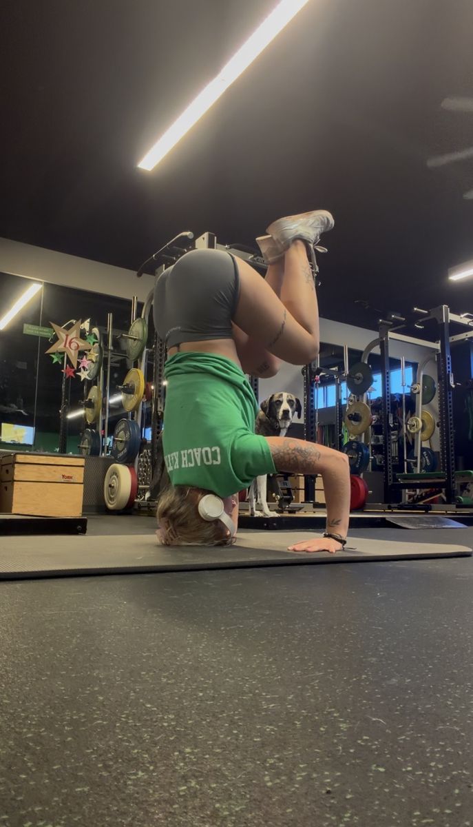 Kat holding a headstand on a mat in the gym