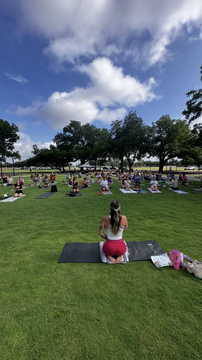 Sami kneeling on her mat leading a large outdoor yoga class